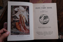 Open book titled 'The Olive Fairy Book' held by a person.