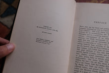 Open book with text held by a hand, showing a preface section.