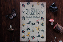 Book titled 'The Winter Garden' by Stanley B. Whitehead on a wooden surface with decorative elements.