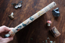 Decorative book spine with nature-themed illustrations on a wooden surface.