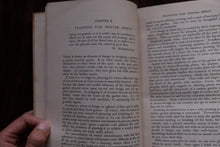 Hand holding an open book with text on a dark background
