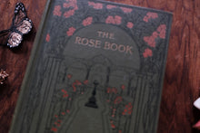 Book titled 'The Rose Book' with decorative cover on a wooden surface