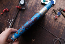 Spine of a notebook on a wooden surface with various items around