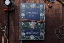 Book titled 'Janet Darney's Story' by Sarah Doudney on a wooden surface with decorative elements.