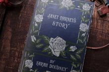 Book titled 'Janet Darney's Story' by Sarah Doudney with floral design on a wooden surface.
