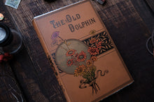 Vintage book titled 'The Old Dolphin' with decorative cover on a wooden surface