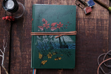 Green notebook with floral designs on a wooden surface