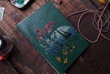 Green notebook with floral design on a wooden surface