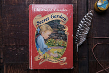 Vintage book titled 'Secret Garden' by Frances H. Burnett on a wooden surface with a feather.