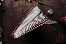 Open book on a wooden surface with tools in the background
