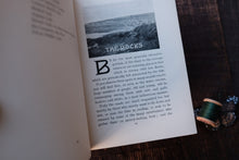 Open book with a black and white photograph and text on a wooden surface.