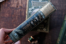 Vintage book with decorative cover held by a hand on a wooden surface
