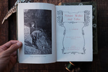 Open book titled 'Nature Walks and Talks' with a black and white photo inside, held by a hand on a wooden surface.