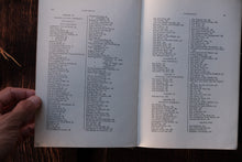 Open book with alphabetical index held by a hand on a wooden surface