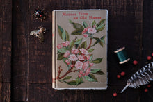 Vintage book with floral design on a wooden surface with decorative items.