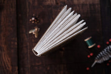 Open book on a wooden surface with sewing materials in the background