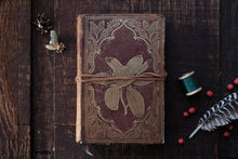 Decorative notebook with floral design on a wooden surface with decorative items.