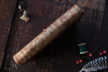 Decorative book spine on a dark wooden surface with sewing materials.
