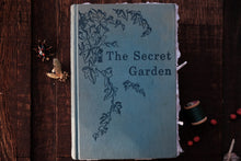 Book titled 'The Secret Garden' on a wooden surface with decorative elements.