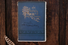 Blue book titled 'The Stories of the Trees' on a wooden surface with a feather.