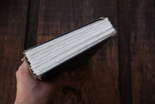 Hand holding a book against a wooden background