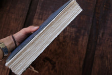 Hand holding a thick book with a wooden surface in the background