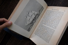 Open book with a black and white illustration of sail boat on a wooden surface