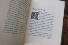 Open book with text and a decorative chapter heading on a wooden surface