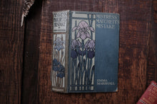 Vintage book titled 'Mistress Matchetti's Mistake' by Emma Marshall on a wooden surface.