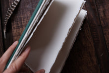 Hand holding a sketchbook open with deckle edge paper