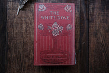 Red book titled 'The White Dove' on a wooden surface
