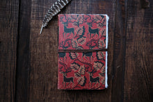 Red notebook with deer pattern on a wooden surface