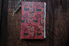 Red notebook with black animal patterns on a wooden surface