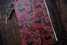 Red notebook with deer pattern on a wooden surface