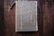 Book titled 'Our Native Trees' by Harriet L. Keeler on a wooden surface with a feather.