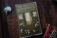 Book titled 'The House of Happiness' by Kate Langley Bosher on a wooden surface.